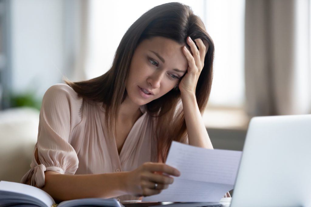 Unhappy woman holding paper, reading bad news in letter