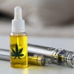 Organic extra virgin cannabinoid oil with vipe pen system against home background. Medical marijuana treatment concept