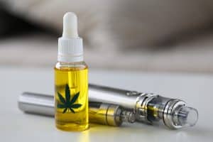 Organic extra virgin cannabinoid oil with vipe pen system against home background. Medical marijuana treatment concept