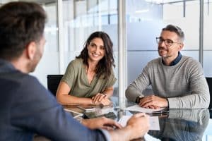 Happy middle aged couple meeting loan advisor to buy a new home.